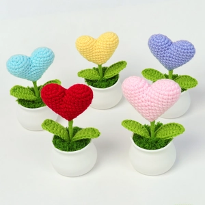 Set of five colorful crochet heart mini potted plants in white ceramic pots with green grass