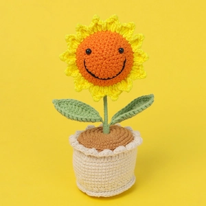 Close-up of handmade crochet sunflower pot with a smiling face and orange petals