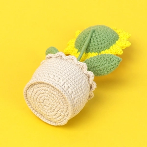 Detailed knit texture of handmade crochet sunflower plant in cream colored knitted pot