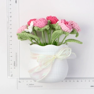 Macro detail of handmade crochet roses in a white ceramic pot with measuring rulers
