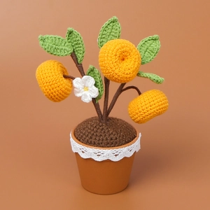 Detail van handgehaakte sinaasappelboom met groene bladeren en kanten bloempot