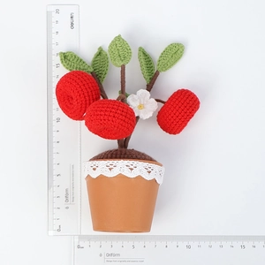 Detailopname van de gehaakte fruitplant in pot met rode bessen en kanten versiering