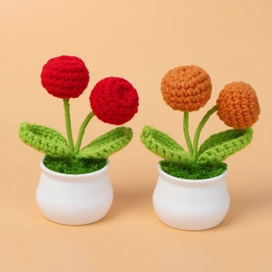 Gros plan de plantes en pot au crochet fait main orange et rouge avec feuilles et pots blancs