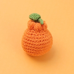 Handmade crochet orange fruit keychain with green leaf on bright orange background