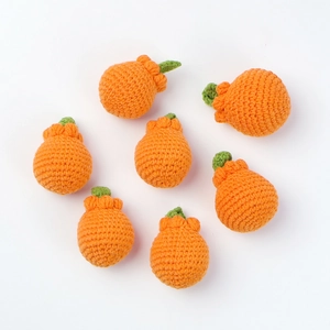 Detailed view of six handmade crochet orange keychains with green leaves on white background