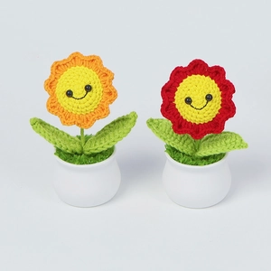Detail view of two handmade crochet sunflower potted plants with smiling faces in white pots
