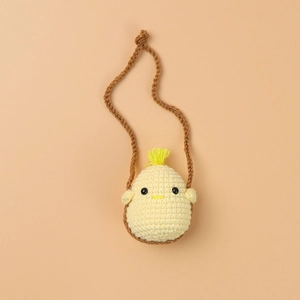Close-up of handmade crochet chick mini bag with soft yellow knit texture and strap