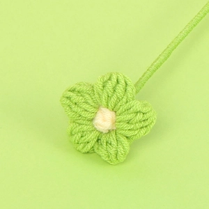 Dettaglio macro di un fiore all'uncinetto fatto a mano verde chiaro con centro giallo