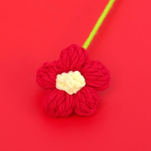Dettaglio macro di un fiore puff fatto a mano all'uncinetto con petali rossi e stelo