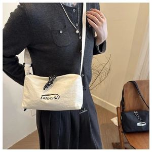 Detail of white FANYISSA crossbody bag featuring a unique drawstring zipper and logo design