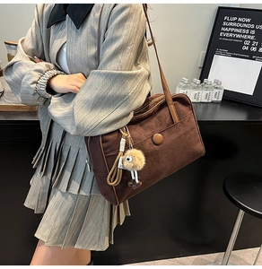 Detail of vintage matte brown tote bag featuring a round buckle and plush monkey charm