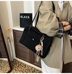 Détail du sac cabas en daim noir avec pompon marron décoratif et boucle minimaliste chic