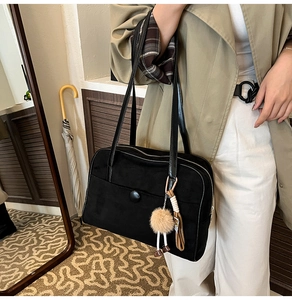 Détail du sac cabas noir mat montrant sa texture suédée et son pendentif en peluche