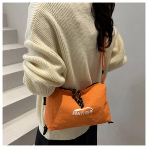 Close-up of bright orange nylon pillow bag featuring a drawstring detail and brand logo