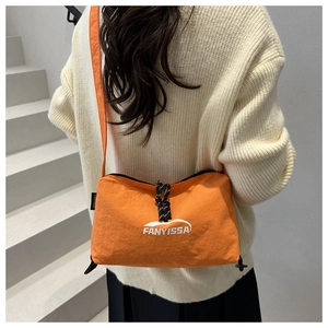 Détail d'une bandoulière en nylon orange avec logo et fermeture éclair sur modèle