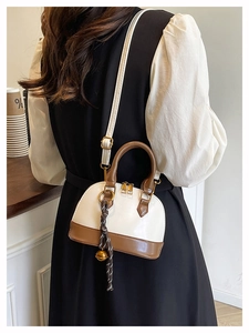 Chic cream and brown shell-shaped crossbody bag shown in a cozy cafe setting