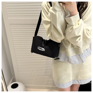 Détail du sac bandoulière minimaliste en toile noire avec texte FANYISSA blanc et sangle