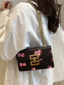 Retro shoulder bag with cherry print, golden chain strap, and metallic lock closure