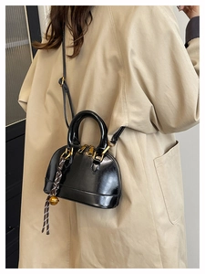 Elegant black glossy shell handbag with golden hardware and braided charm detail