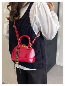 Detail of red shell bag featuring gold hardware and unique woven ball charm