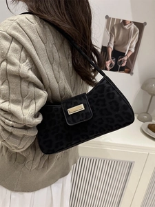 Sac à bandoulière vintage motif léopard noir avec boucle dorée porté par un modèle