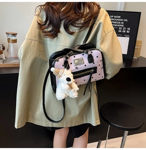 Detail of pink polka dot bag with black leather trim and white plush bear charm