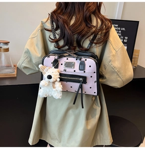 Detailed view of a pink polka dot backpack with a cute white plush bear keychain