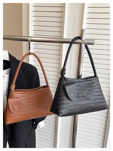 Détail de cabas tressés en marron et noir avec bandoulières tressées et charmes ronds