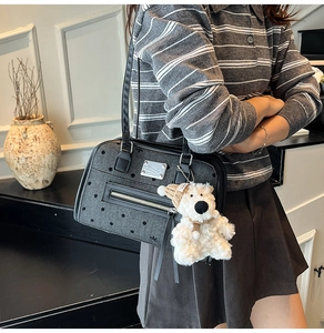 Detail of dark grey polka dot texture bag with cute white bear plush charm on model
