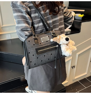 Detailed view of gray polka dot denim bag featuring black tassel zipper and plush puppy charm