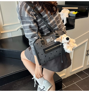 Detail of dark grey polka dot denim bag with black leather straps and plush puppy charm