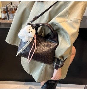 Detailed view of woven texture on dark brown crossbody bag with plush puppy charm