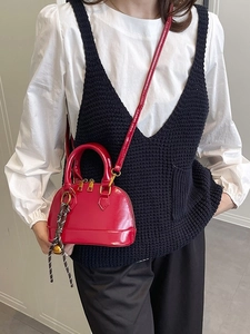 Classic red shell-shaped handbag in glossy leather with gold zipper and striped pendant