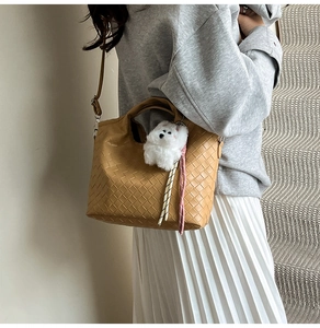 Detail of khaki woven texture bag with a cute plush puppy charm on a crossbody strap