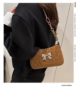 Detail of leopard print baguette bag featuring silver bow accent and resin chain strap
