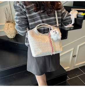 Close-up of cream woven bucket bag texture with a cute plush dog charm accessory