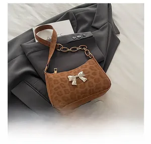 Detail of leopard print crossbody bag with silver butterfly buckle and resin chain