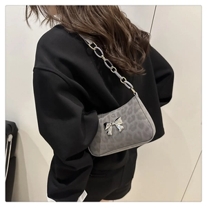 Detail of grey leopard print shoulder bag with silver bow ornament and chain strap
