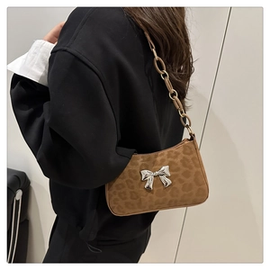 Detail of leopard print crossbody bag with silver butterfly buckle and chain strap