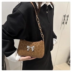 Detail of leopard print suede shoulder bag with polished silver butterfly bow buckle