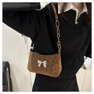 Close-up of leopard print shoulder bag with silver bow accent and metal chain strap