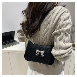 Close-up of black leopard print baguette bag with a silver 3D bow detail and slim strap