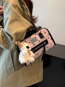 Sac à main rose à pois avec garniture noire et breloque ours en peluche, porté par mannequin