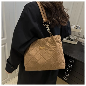 Detail of brown quilted tote bag showing fine stitching and gold metal ring connection