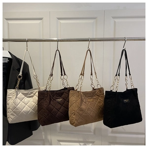 Detail of four quilted tote bags in beige, brown, caramel, and black with metal ring straps