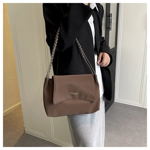 Detail of a brown leather shoulder bag with chain strap and printed lettering design