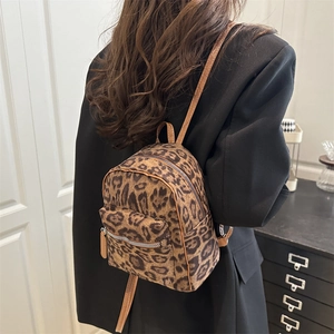Close-up of stylish leopard print mini backpack with brown straps worn by a model
