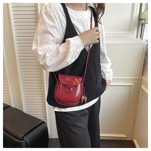 Detail of red glossy mini saddle bag with cute strawberry pendants and metal buckle