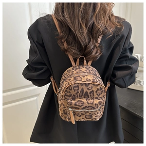 Close-up of a trendy leopard print plush mini backpack shown on a model's back