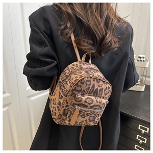Detail of leopard print mini backpack with brown leather straps shown on model